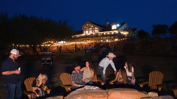 An outdoor seating area with wooden chairs and a stone fire pit.