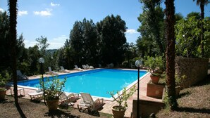 A rectangular swimming pool with a clear blue water surface, surrounded by lounge chairs and potted plants. - Elegant house inside our period villa surrounded by centuries-old park (Marche)