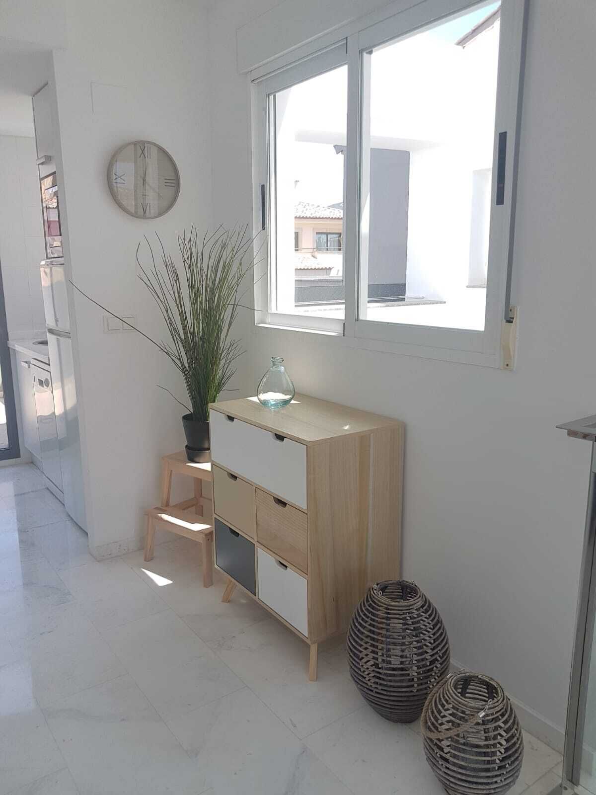 Habitació minimalista amb un armari de fusta, una planta en test i dues cistelles teixides.