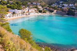 Une ville côtière aux bâtiments blancs, avec une plage et une eau turquoise cristalline.
