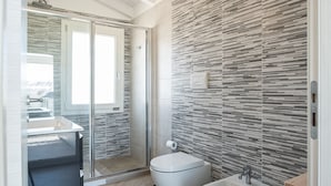 Un bagno moderno con cabina doccia in vetro, un water e un lavandino.
