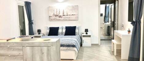 A bedroom with a bed, bedside tables, a desk, and a mirror.