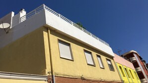 Un edificio con tetto piatto, un'antenna parabolica e un balcone con ringhiera a traliccio.