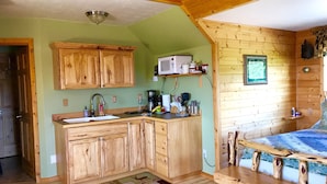 A cozy cabin-style kitchen with wooden cabinets, a microwave, and a coffee maker.