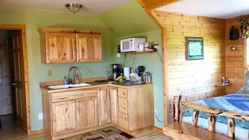 A cozy cabin-style kitchen with wooden cabinets, a microwave, and a coffee maker.