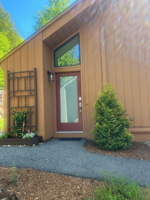 Un bâtiment avec une porte rouge, une petite fenêtre et un portail en métal.