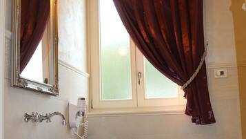 A bathroom with a white sink, a mirror, and a window with curtains.