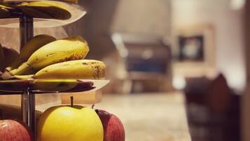 Une présentation de fruits sur un comptoir en marbre, avec des bananes, des pommes et des citrons.