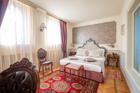 Un dormitorio con una cama grande, una silla, una mesita de noche y una lámpara de pared.