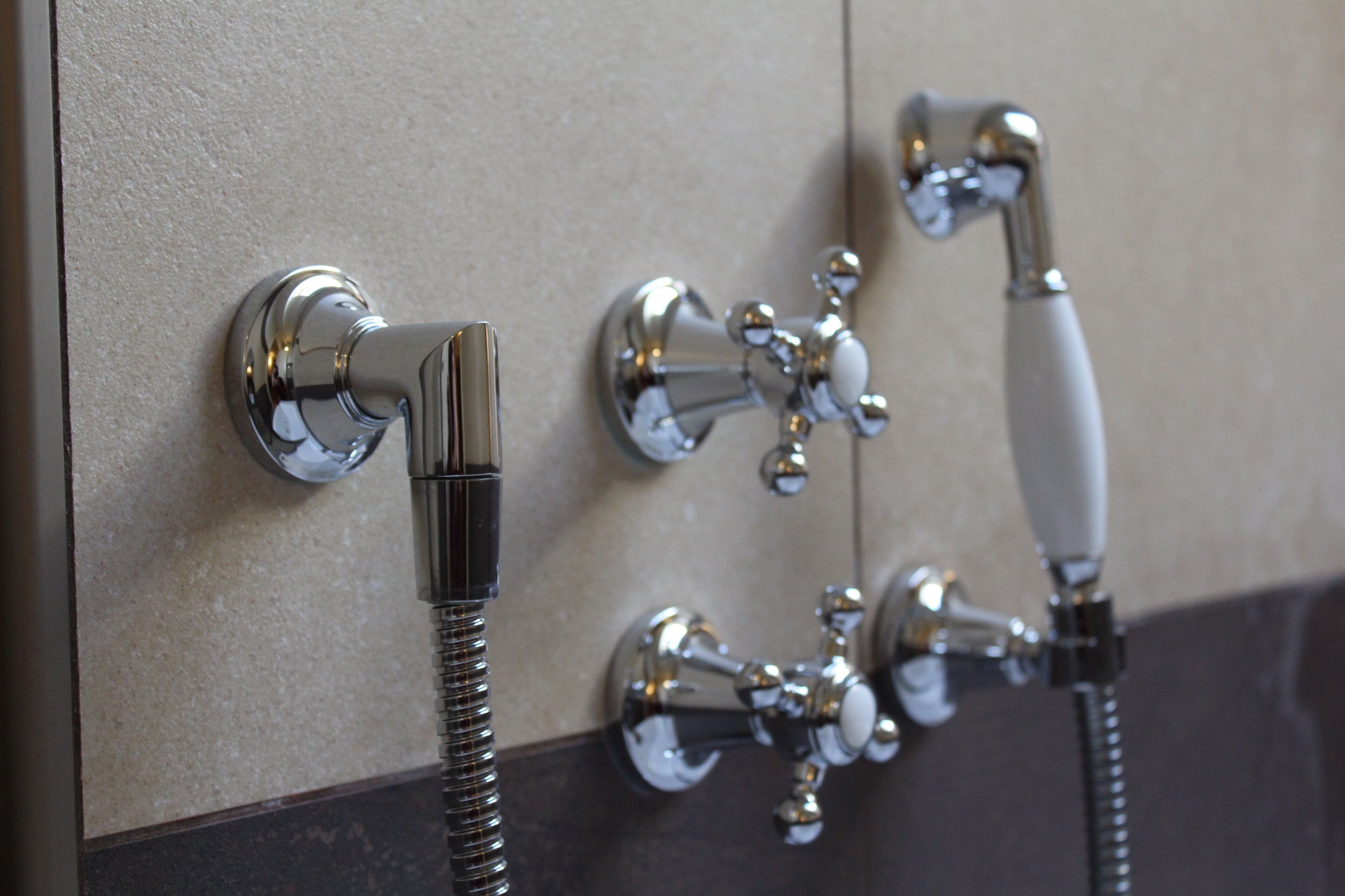 Een badkamer met een in de muur gemonteerde douche en een handdouche.