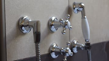 Een badkamer met een in de muur gemonteerde douche en een handdouche.
