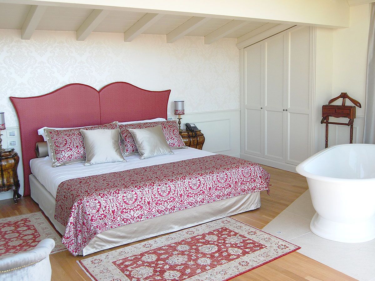 Un dormitorio con una cama grande, una bañera blanca y un aparador de madera.