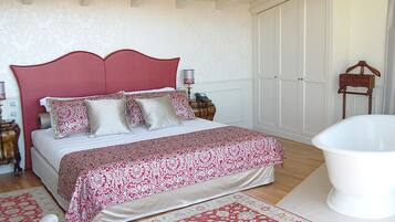 Un dormitorio con una cama grande, una bañera blanca y un aparador de madera.
