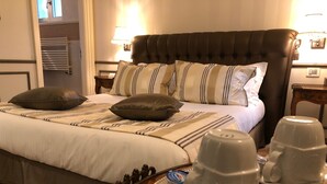 A neatly made bed with striped bedding, a tray with cups and a spoon, and a lamp on the nightstand. - Relais Colle San Pietro (Verona)