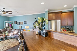 A modern kitchen with wooden cabinets, stainless steel appliances, and a wooden dining table. - Savorn's Boutique Brownstone – 11-Bed Group Getaway Near River & Lake (Rancho Cordova)