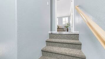 Un escalier recouvert d’une moquette à motifs et doté d’une rampe en bois, menant à une porte.
