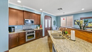 A kitchen with wooden cabinets, stainless steel appliances, a granite countertop, and a sink.