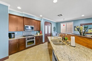 A kitchen with wooden cabinets, stainless steel appliances, a granite countertop, and a sink. - Savorn's Boutique Brownstone – 11-Bed Group Getaway Near River & Lake (Rancho Cordova)
