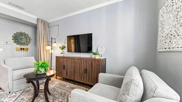 Uma sala de estar moderna com sofá, poltrona, televisão, painel decorativo e um armário.