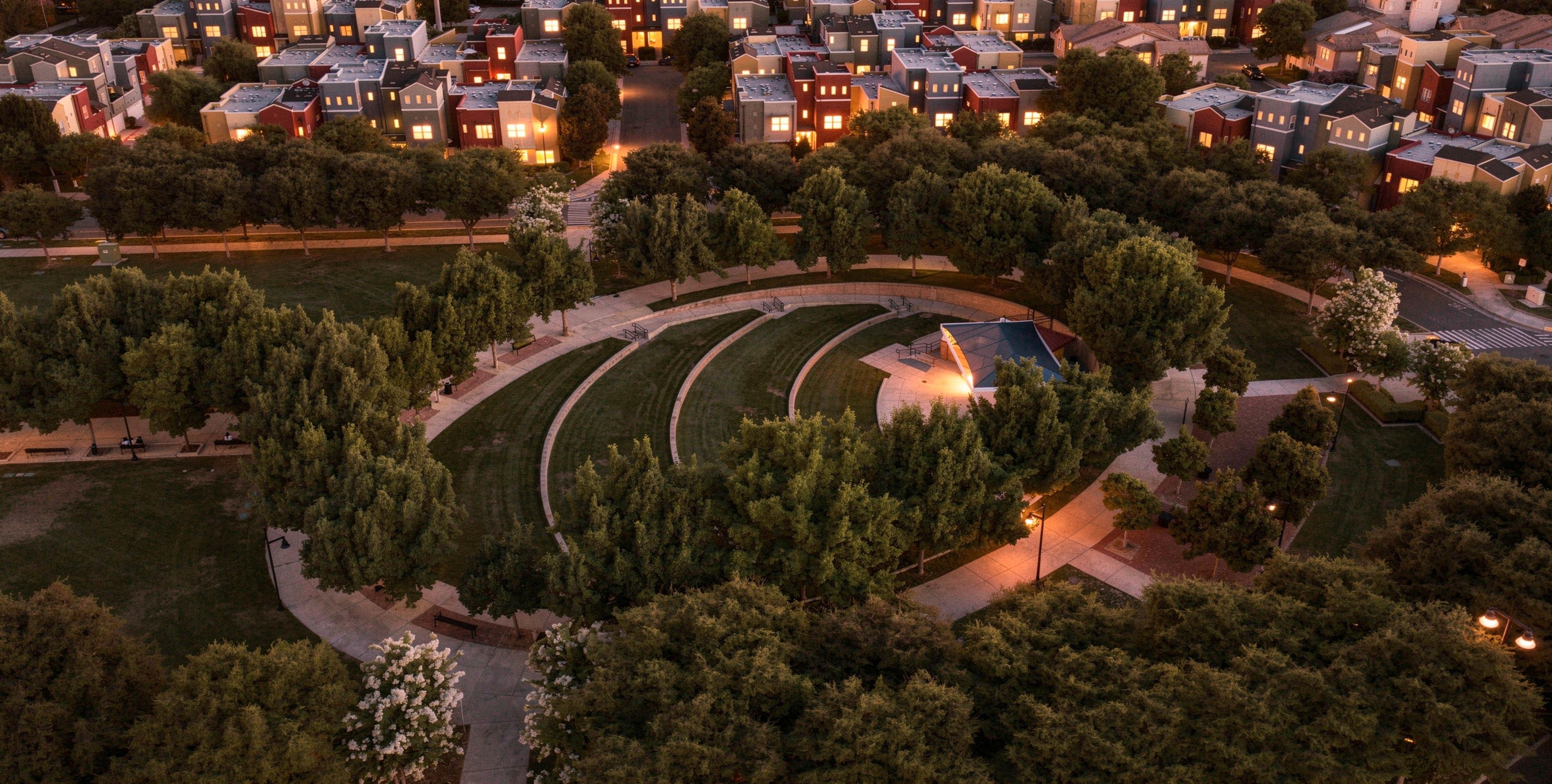 Un quartier résidentiel comprenant plusieurs maisons, un parc circulaire central et un petit bâtiment doté d’un toit.