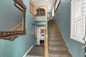 Un escalier avec une rampe en bois et des marches recouvertes de moquette, menant à un palier doté d’une porte.