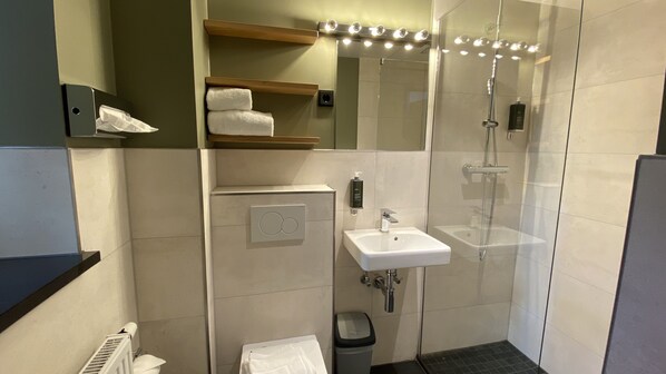 A modern bathroom with a glass-enclosed shower, a white sink, and a towel rack.