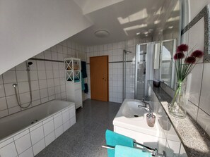 Ein modernes Badezimmer mit einer Badewanne, einer Dusche und einem Waschbecken.