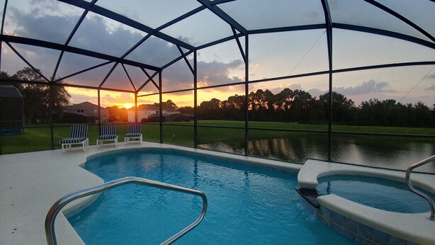 A swimming pool with a view of a sunset over a residential area. - Spectacular Lake View - Game/Media Room - Vacation Home Close to Disney (Kissimmee)