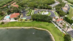 An aerial view of a residential area with a swimming pool, landscaped gardens, and a roundabout. - Spectacular Lake View - Game/Media Room - Vacation Home Close to Disney (Kissimmee)