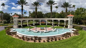 A fountain with dolphins, surrounded by a white gazebo, palm trees, and a well-maintained lawn. - Spectacular Lake View - Game/Media Room - Vacation Home Close to Disney (Kissimmee)