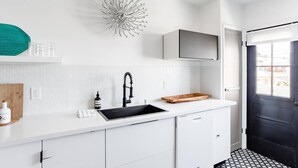 A modern kitchen with a white countertop, black sink, and a decorative wall piece. - Sun filled + Airy Large 2 Bedroom apt in West adam’s (Los Angeles)