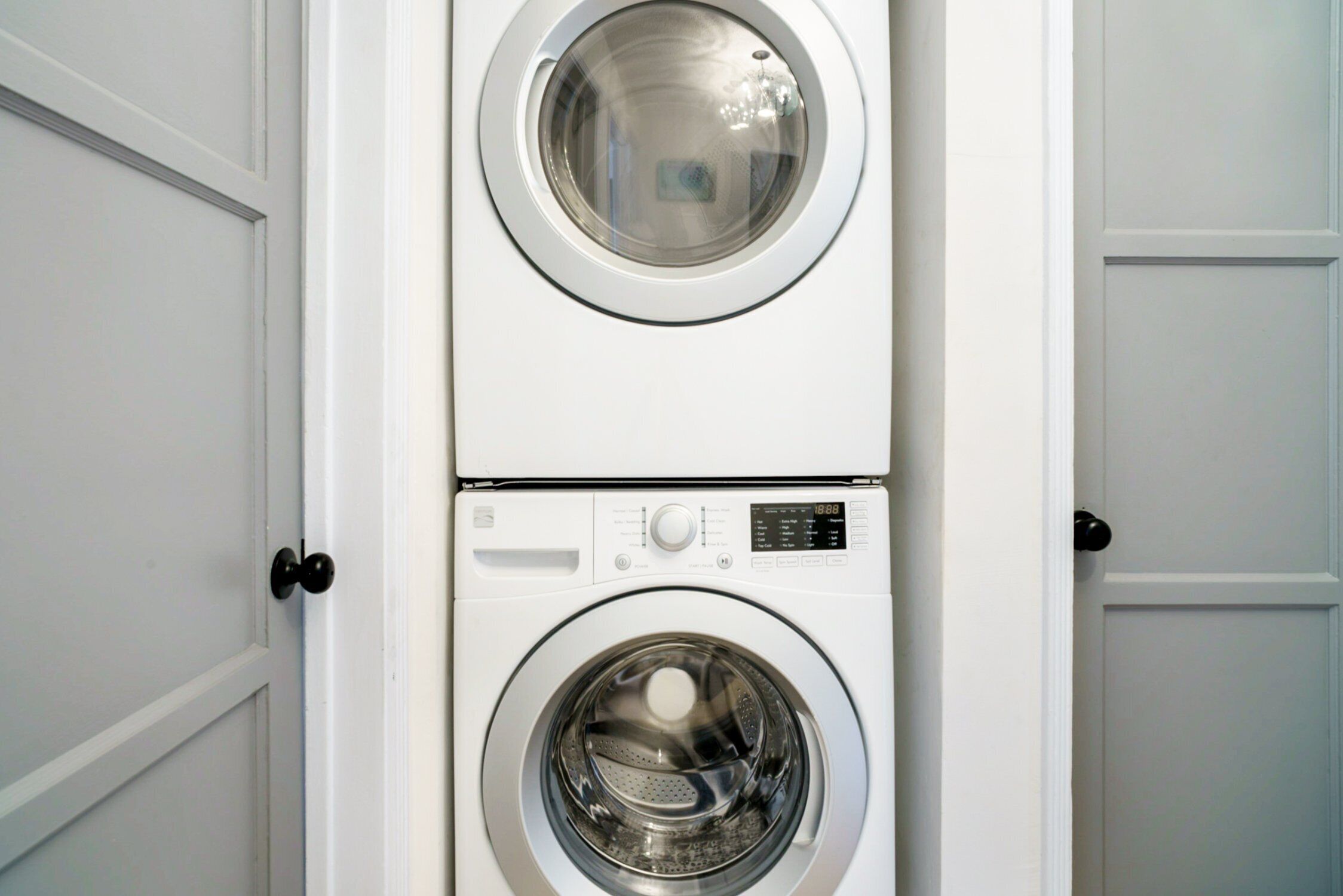 A stacked washer and dryer unit in a white-walled room.