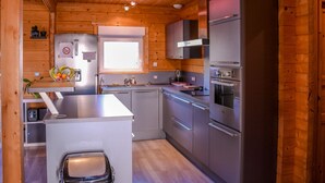 Une cuisine moderne dotée d’appareils électroménagers en acier inoxydable, de murs en bois et d’une fenêtre laissant entrer la lumière naturelle.