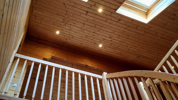 Un intérieur en bois agrémenté de lucarnes, un balcon avec une balustrade et un escalier.