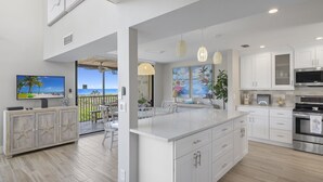 A modern kitchen with white cabinetry, a large island, and a dining area with a view.