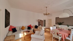 A modern living room with a sofa set, a dining table with chairs, and a chandelier. - Modern apartment with large balcony 110m² / free garage with e-charging station (Wien)