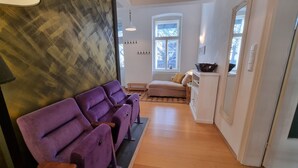A hallway with a purple sofa, a white cabinet, and a large window. - Modern apartment with large balcony 110m² / free garage with e-charging station (Wien)