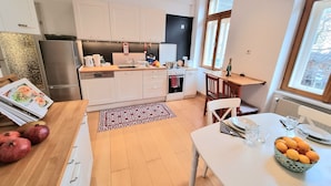 A modern kitchen with white cabinets, a built-in oven, and a dining area with a table and chairs. - Modern apartment with large balcony 110m² / free garage with e-charging station (Wien)