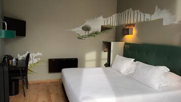 A hotel room with a bed, a desk, a chair, a TV, and a wall-mounted shelf.