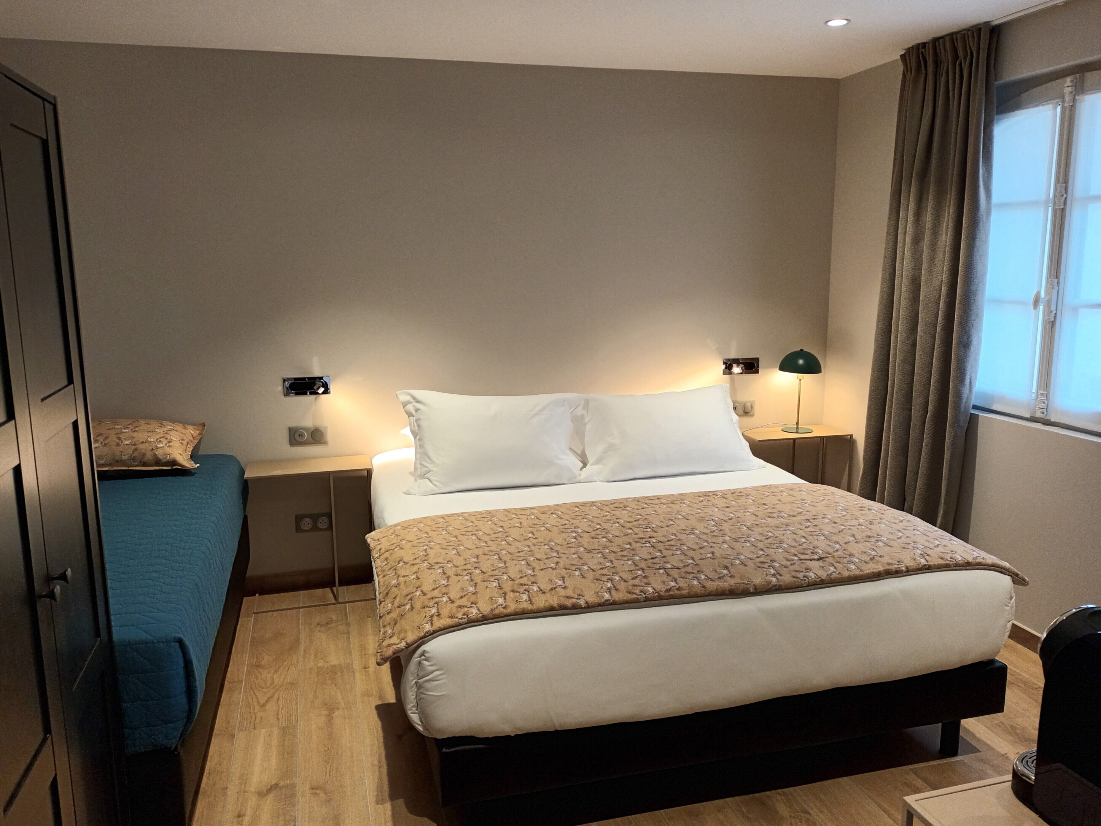 Una habitación de hotel con cama, mesitas de noche, escritorio y armario.