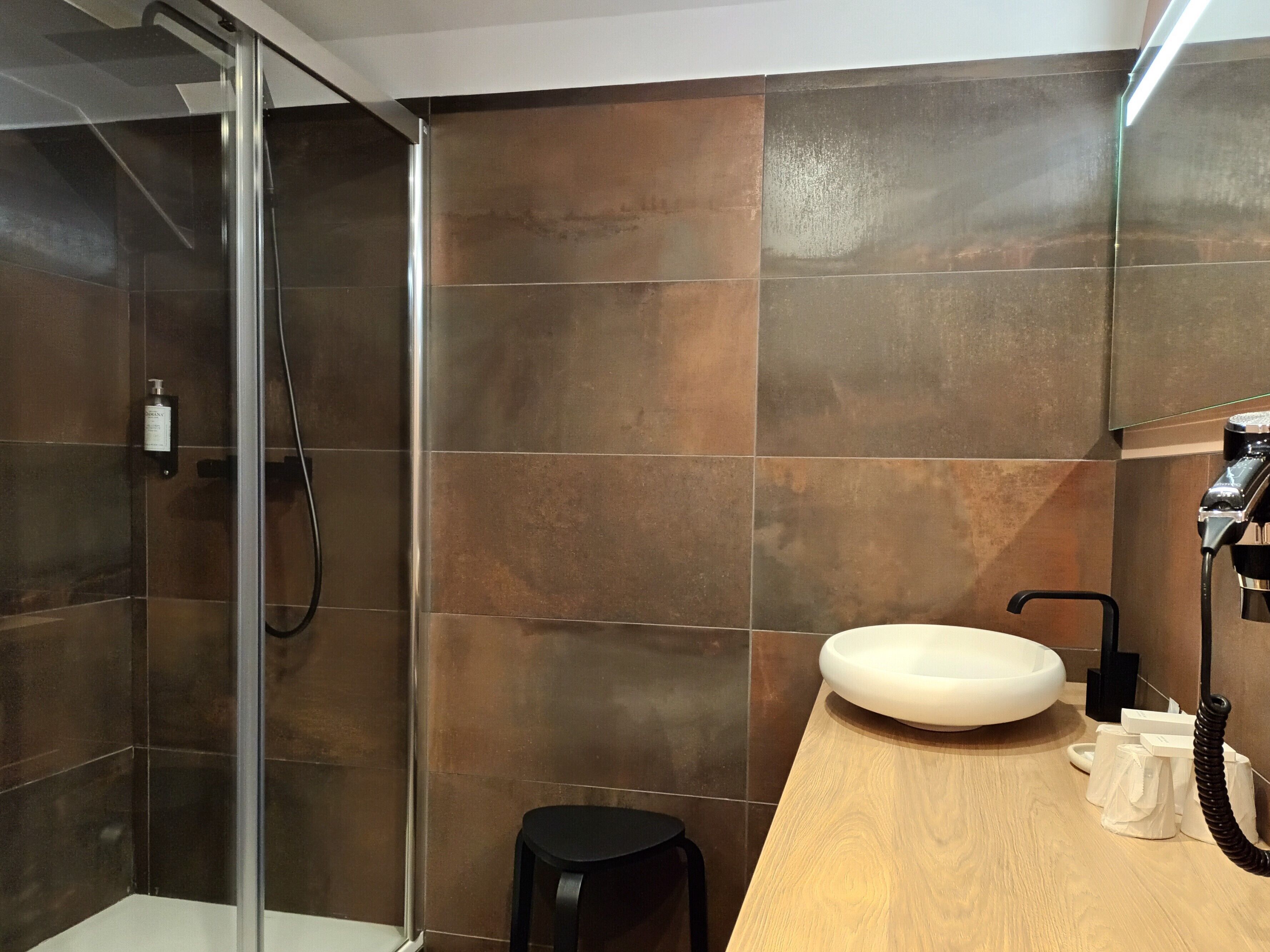 A modern bathroom with a glass shower enclosure, a wooden vanity with a sink, and a mirror.