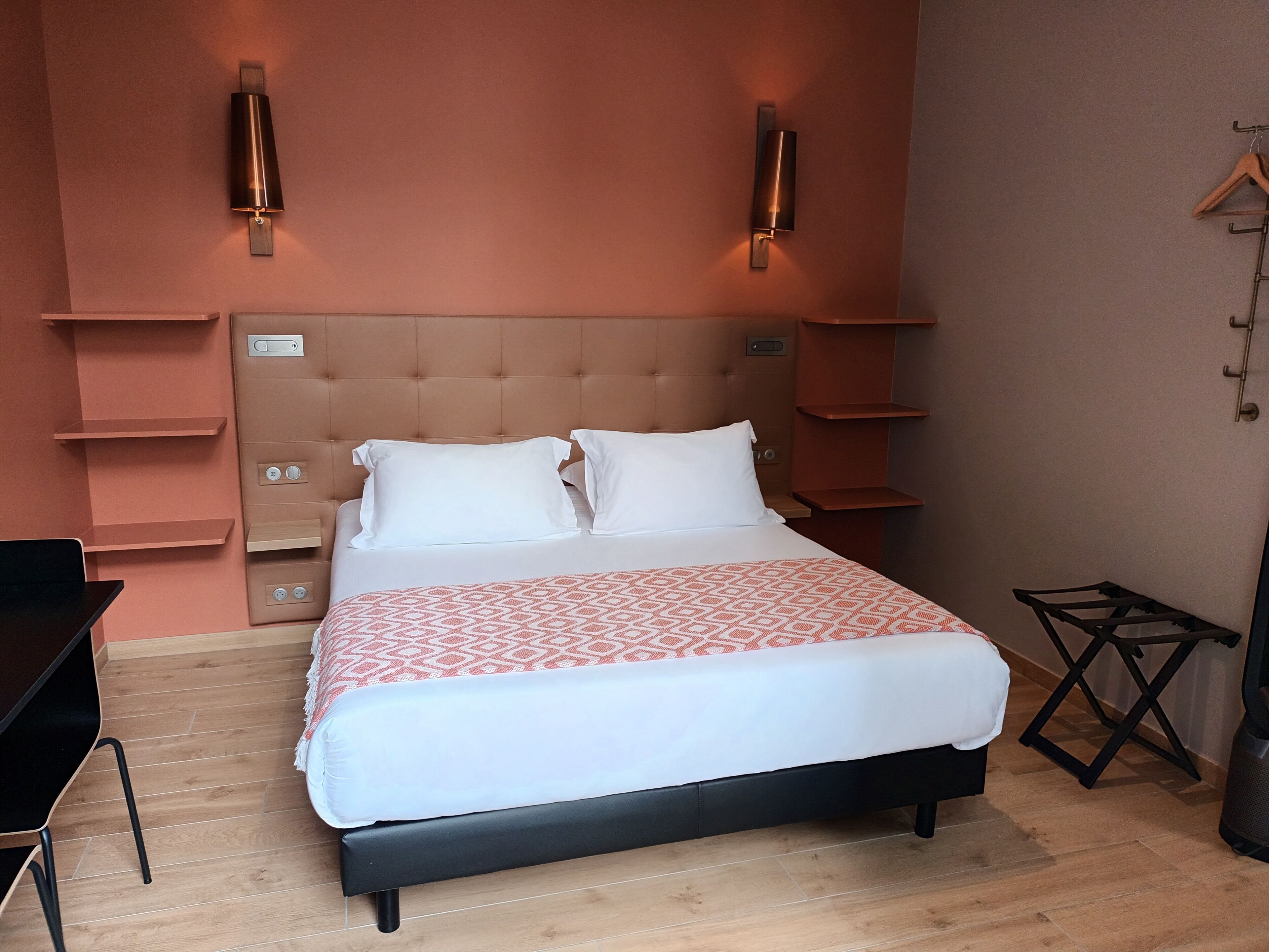 Une chambre à coucher avec un lit, des tables de chevet, un bureau et une chaise.
