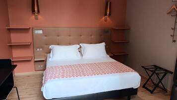 A bedroom with a bed, bedside tables, a desk, and a chair.