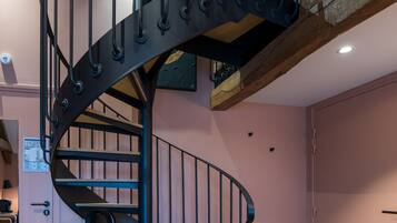 A spiral staircase with black railings and wooden steps, leading to an upper floor.