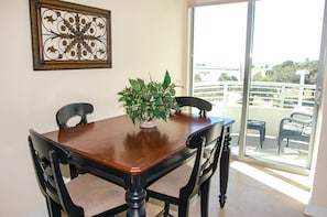 Enjoy meals in this dining area with a table and chairs, surrounded by a potted plant and a view of the outdoors.