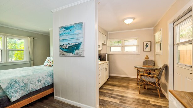 A compact room with a bed, a dining area with a table and chairs, a kitchen area, and a painting on the wall. - Newly remodeled Parakeet cottage!  Walking distance to beach, restaurants, shops! (Sanibel)