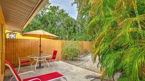 A patio with a table and chairs, a wooden fence, and a palm tree. - Newly remodeled Parakeet cottage!  Walking distance to beach, restaurants, shops! (Sanibel)