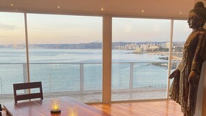 A dining area with a wooden table and chairs, a statue, and a view of a cityscape across a body of water. - Asian Style Home with the Best View in Viña! (viña del mar)