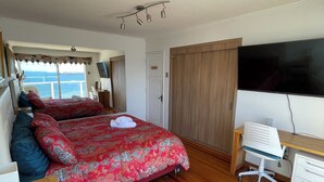 A bedroom with a large bed, a desk, a chair, and a TV. - Asian Style Home with the Best View in Viña! (viña del mar)