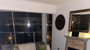 A living room with a fireplace, a sofa, a coffee table with candles, and a view of the city at night. - Asian Style Home with the Best View in Viña! (viña del mar)
